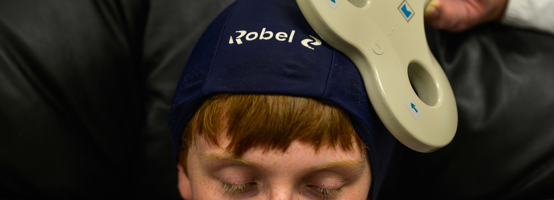 Young Will Robeson closes his eyes as he undergoes transcranial magnetic stimulation by way of a magnetic wand.