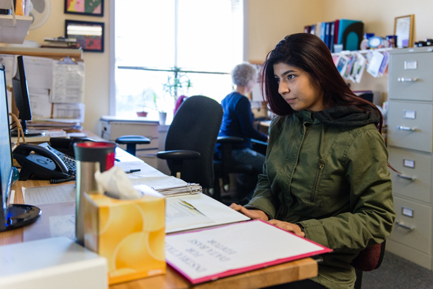 Nubia Flores Miranda types at a computer in her counseling office