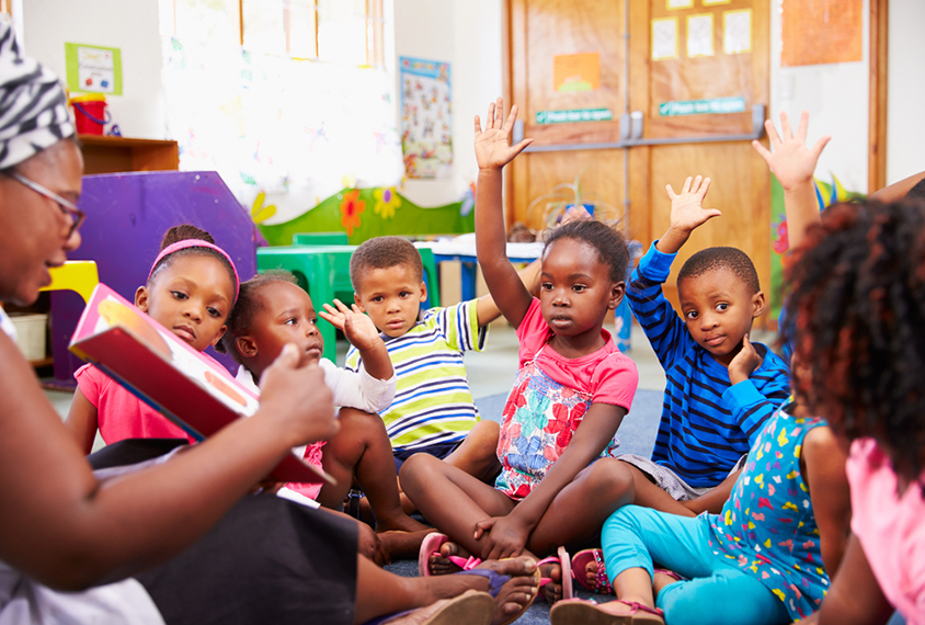 Children in pre-school sitting around a learning circle.