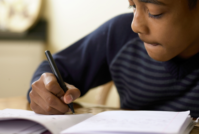 child writing on a piece of paper with intense focus.