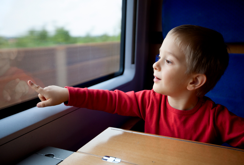 Boy pointing out moving train window