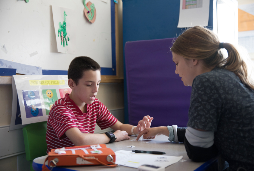 Child and therapist/clinician with picture and letter cards in classroom