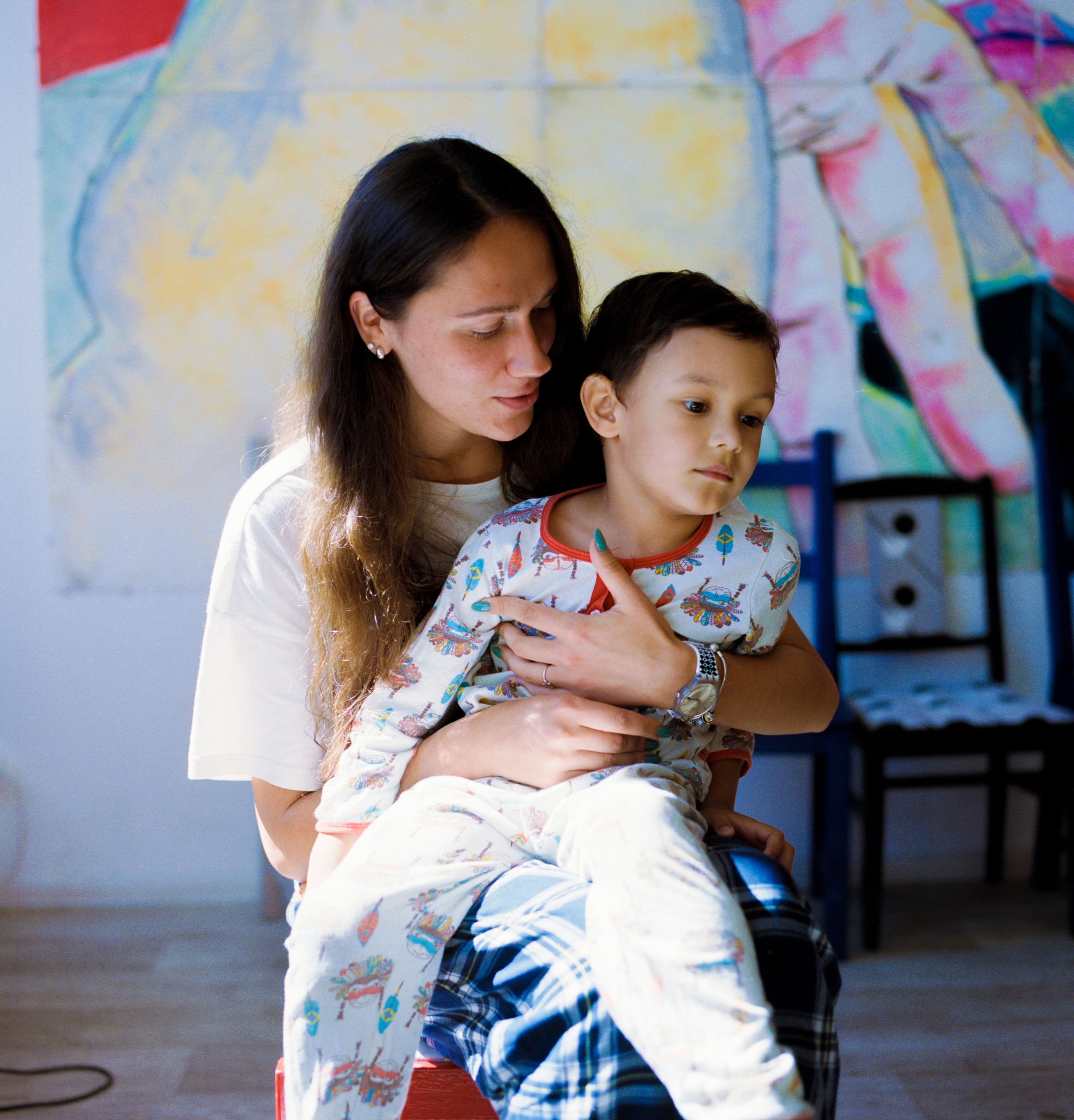 A young woman volunteer sits with Misha at the slumber party. Every autistic child at the camp has a personal volunteer to support and accompany them.