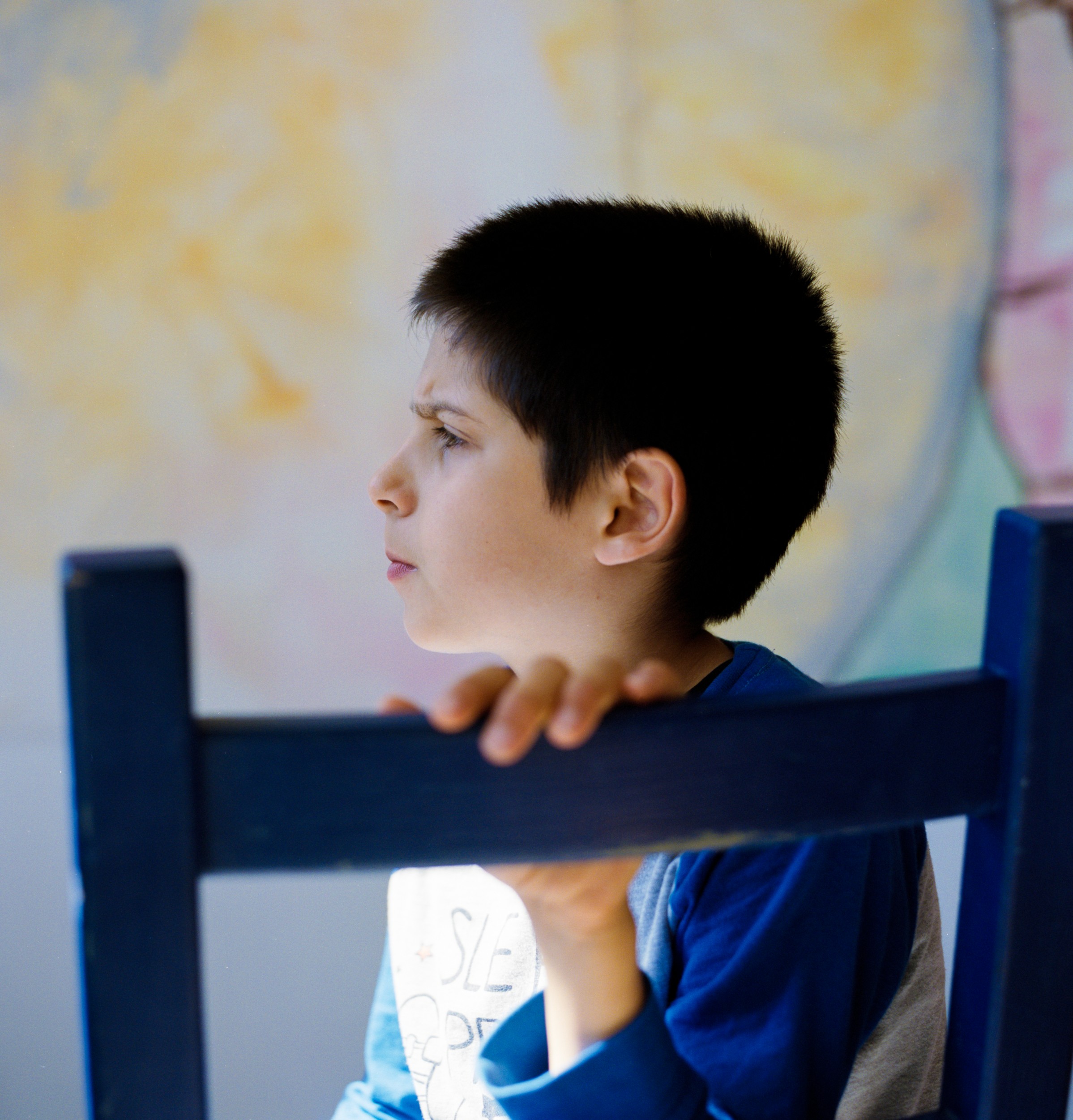 Young boy at a city camp for autistic children sits in the colorful playroom.