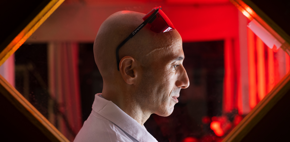 Ofer Yizhar in his lab, framed by rectangular window and a red background.