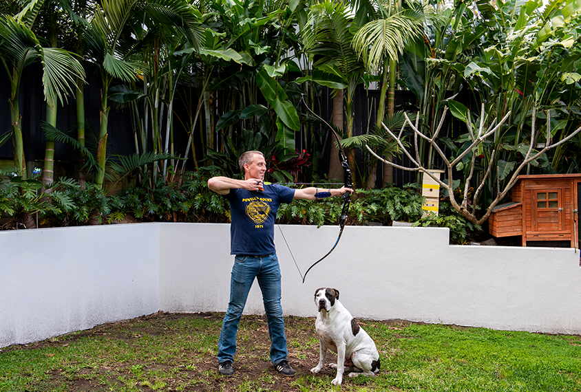 Scientist Ethan Scott takes aim with a bow and arrow in his backyard.