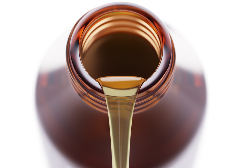 Closeup photo of a liquid being poured out of a brown bottle.