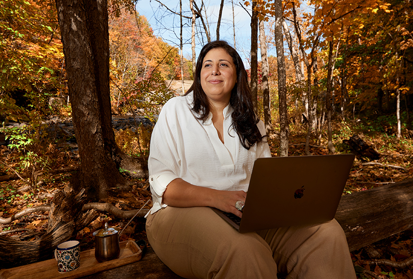 Mayada Elsabbagh with her laptop and coffee, in the woods near her home.