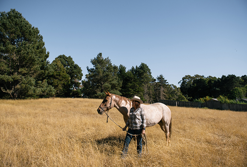 Judy Van De Water with her horse Hank in a field.