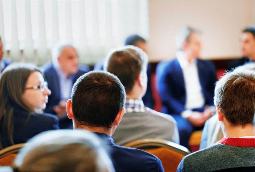 A group of people in business attire is seated and having a conversation.