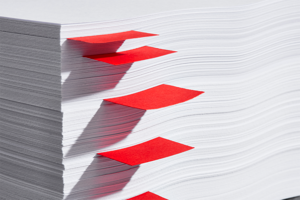 Image of a series of red sticky notes protruding from a stack of white paper.