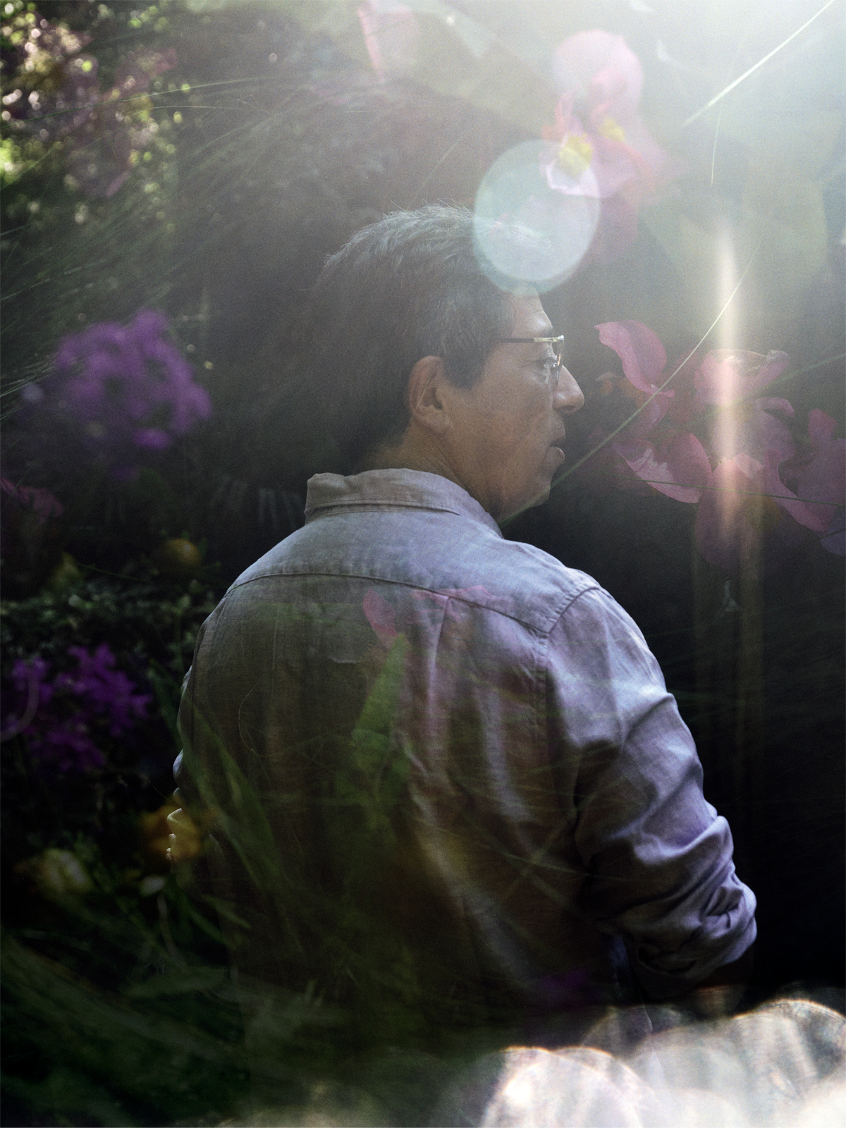 Photograph of Martin Giurfa in a purple shirt standing outside with purple flowers.