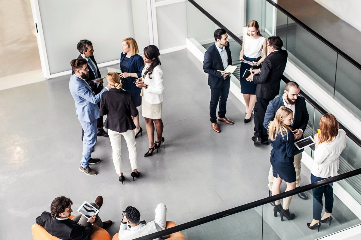 Stock photograph of several groups of people in business attire standing and having conversations.