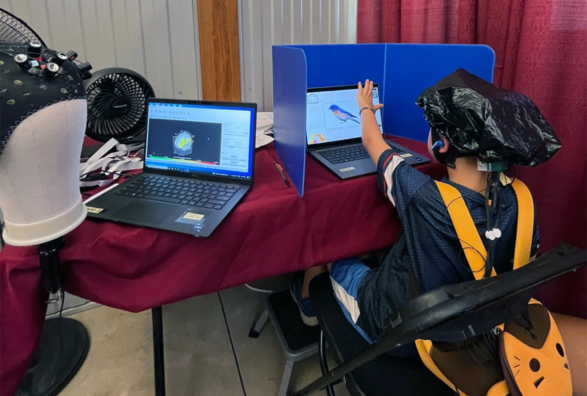 Photograph of a child sitting at a laptop and performing an executive function test.