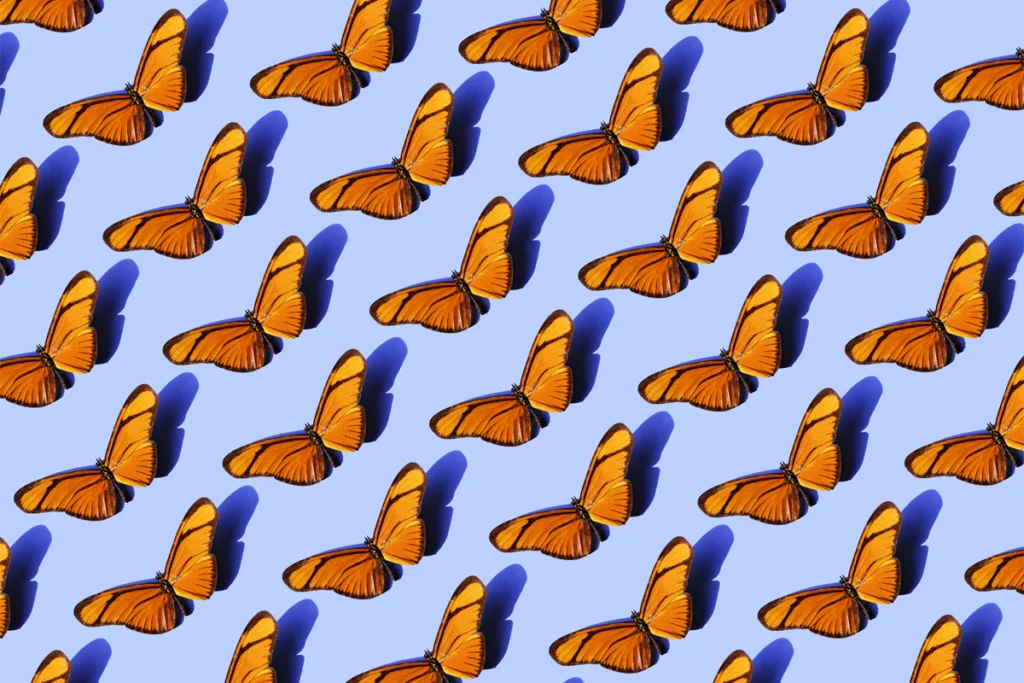 A repeating pattern of orange butterflies against a blue background.