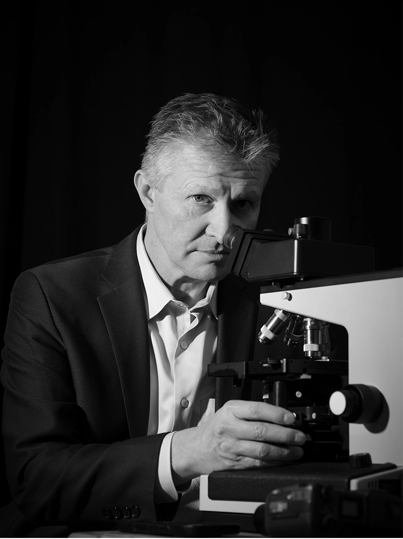 Black-and-white photograph of Bryan Jones looking into a microscope.