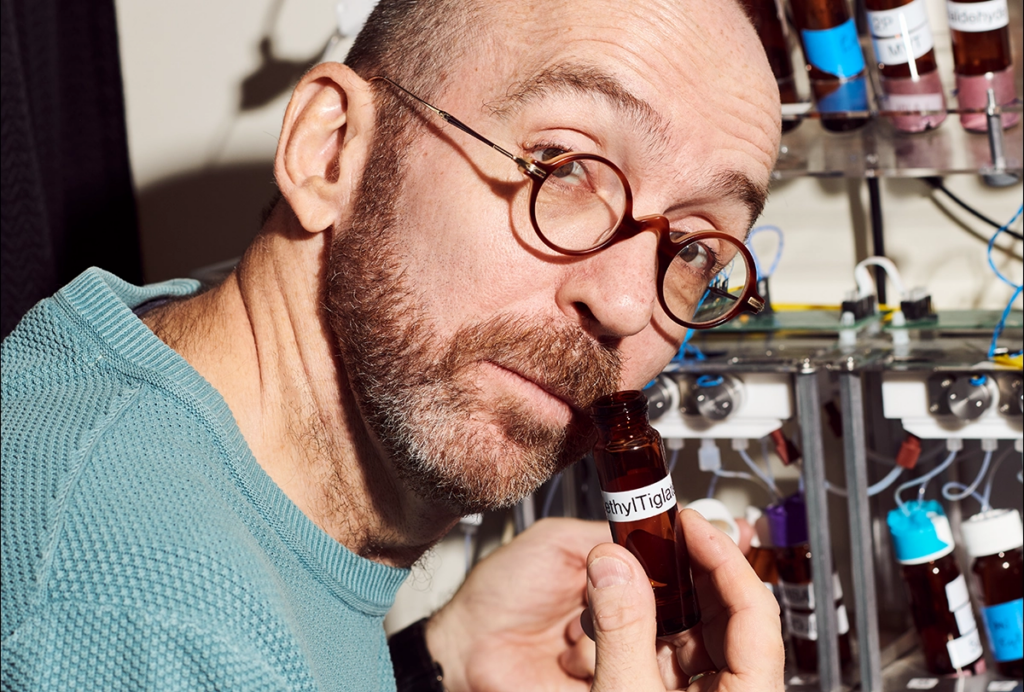 Dima Rinberg smells one of the compounds in his lab, looking at camera with a quizzical expression.