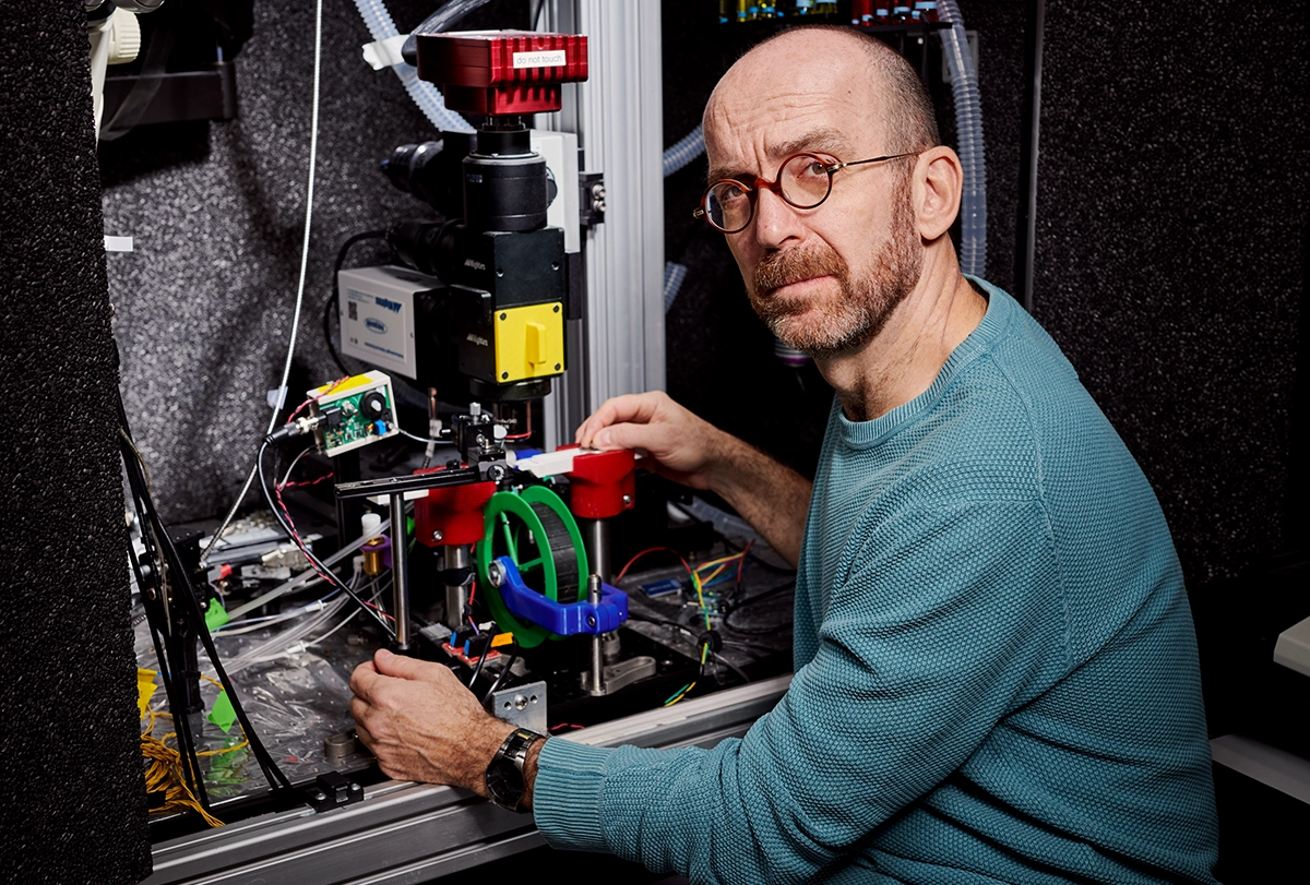 Dima Rinberg seated in front of a customized lab setup including a mouse wheel.