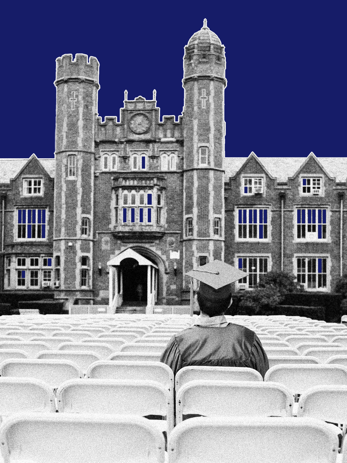 A student in a cap and gown sits alone in a row of folding chairs in front of a large brick building.